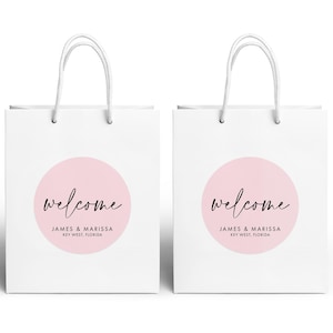 two white paper shopping bags with the word "Welcome" printed on them.