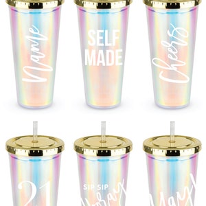 May include: Six iridescent tumblers with gold lids and straws. Each tumbler has a different white design, including "Name", "Self Made", "Cheers", "21", "Hooray", and "Yay".