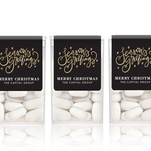 May include: Three clear plastic containers filled with white mints. Each container has a black label with gold script that reads "Season's Greetings" and "Merry Christmas The Capital Group".