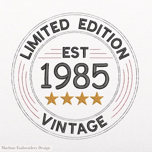May include: Embroidered circular design with the text "LIMITED EDITION" and "VINTAGE". The year "1985" is prominently displayed, along with four gold stars. The design is in black, red, and gold on a white background.
