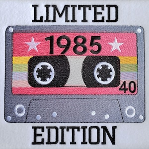 May include: Embroidered design of a retro cassette tape with the text "LIMITED EDITION 1985 40". The cassette has a pink centre with white stars and a rainbow stripe. The tape is grey with black text.