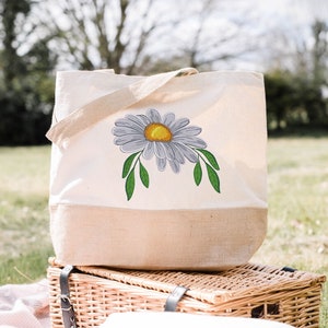 Daisy embroidery design featured on a shopping bag.