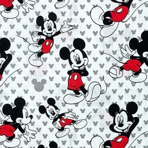 May include: White fabric featuring a repeating pattern of Mickey Mouse in various poses. Mickey is depicted in his classic outfit with red shorts, black ears, and white gloves. The background is dotted with small gray Mickey Mouse head silhouettes.