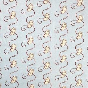 May include: Light blue fabric with a repeating pattern of cartoon monkeys. Each monkey is cream-colored with brown arms, legs, and a tail. The monkeys are arranged in vertical rows, creating a playful and whimsical design.