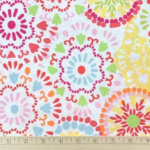 May include: White fabric with a colorful floral pattern. The design features circular motifs in shades of pink, red, orange, yellow, green, and blue. The fabric is decorated with stylized flower and leaf shapes.