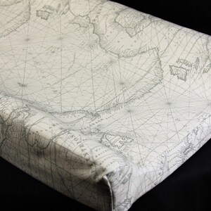 May include: A white changing pad cover with a vintage nautical map design in gray. The map features lines of longitude and latitude, as well as landmasses and islands.