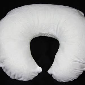 May include: A white, U-shaped pregnancy pillow with a soft, plush fabric cover. The pillow is designed to provide support and comfort during pregnancy and breastfeeding.