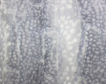 Peut inclure: Gros plan sur un tissu en fausse fourrure doux, gris et blanc, avec un motif tacheté. Le tissu a une texture duveteuse et un léger brillant.