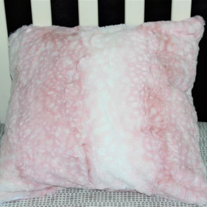 May include: A pink and white faux fur throw pillow with a soft, fluffy texture.