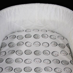 May include: White baby crib with a white and gray fitted sheet featuring a repeating pattern of gray moons with smiling faces.