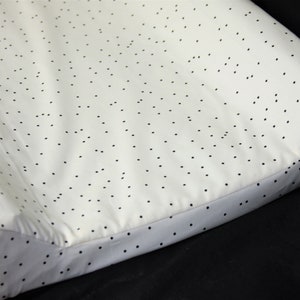 May include: White changing mat with a black polka dot pattern. The mat has a raised edge around the perimeter.