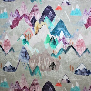May include: A colorful fabric with a repeating pattern of mountains in shades of blue, purple, pink, green, and white. The mountains are outlined in white and have a watercolor effect. The background is a light gray.
