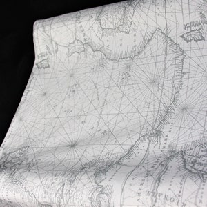 以下が含まれることがあります： グレーと白の航海図柄がプリントされた白い生地。地図にはコンパスローズと経度と緯度の線が描かれています。