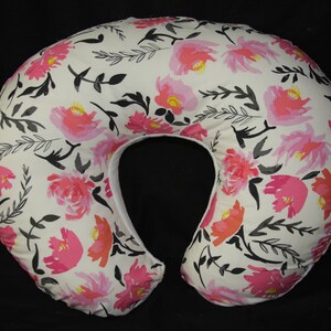 May include: A white nursing pillow with a floral print featuring pink and black flowers on a white background.