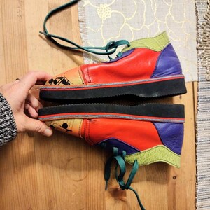 Puede incluir: Un par de zapatos de cuero multicolores con cordones verdes. Los zapatos tienen una suela de goma negra y est&aacute;n decorados con un dise&ntilde;o colorido.