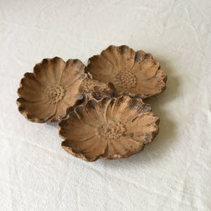 K&ouml;nnte beinhalten: Ein Set aus drei terracotta-Blumenschalen. Die Schalen sind miteinander verbunden und haben ein rustikales, erdiges Aussehen.