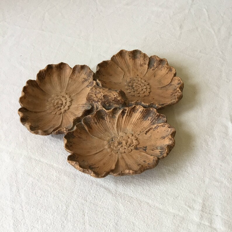 K&ouml;nnte beinhalten: Ein Set aus drei terracotta-Blumenschalen. Die Schalen sind miteinander verbunden und haben ein rustikales, erdiges Aussehen.
