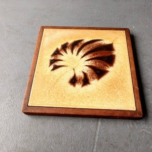 May include: A square ceramic tile with a brown and white swirl design, framed in a dark wood frame.