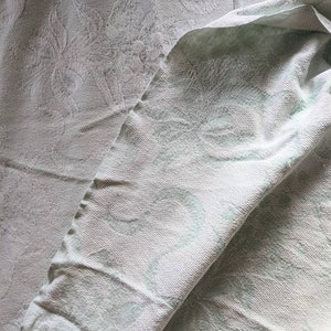 May include: A white textured blanket with a subtle pattern. The blanket is folded in half and the edges are slightly curled.