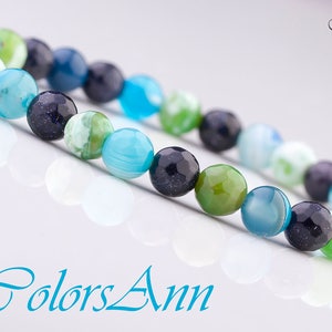 May include: A bracelet made of blue, green, and black agate beads. The beads are round and have a polished finish.