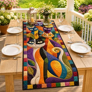 Può includere: Un runner da tavola rettangolare caratterizzato da un vivace design trapuntato di gatti stilizzati nei toni dell'arancione, viola, blu e nero, bordato da un motivo a mosaico colorato. Il runner è posizionato su un tavolo in legno con piatti.