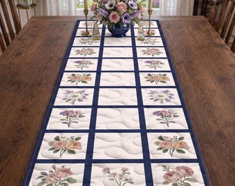 Puede incluir: Un camino de mesa rectangular con un patrón de cuadrícula de cuadrados blancos con textura acolchada ondulada, separados por bordes azul oscuro. Cada cuadrado contiene una ilustración impresa de varias flores, incluyendo rosas y lavanda.