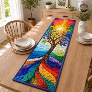 Könnte beinhalten: Ein rechteckiger, gesteppter Tischläufer mit einem lebendigen, mehrfarbigen Baummotiv. Der Baumstamm ist braun, mit Ästen, die sich in einem Sonnenstrahlenmuster aus Gelb, Orange und Rot erstrecken. Die Basis zeigt fließende Regenbogenwellen.