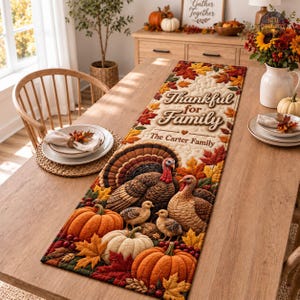 May include: A rectangular quilted table runner featuring a Thanksgiving theme with turkeys, chicks, and pumpkins surrounded by autumn leaves. The text reads Thankful for Family and The Carter Family. The design includes warm orange, brown, and red tones.