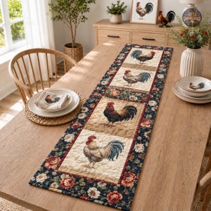 May include: A rectangular quilted table runner featuring a repeating pattern of roosters on beige squares, bordered by a dark navy blue fabric with a floral print of red and white flowers. A matching cloth napkin with a rooster print sits on a plate.