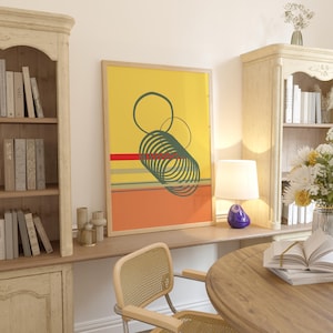 Op de afbeelding: Abstracte kunstprint met een gele achtergrond, rode, groene en oranje geometrische vormen. De print is ingelijst in een naturel houten lijst en hangt aan een witte muur.