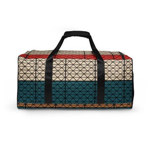 May include: A duffel bag featuring a geometric grid pattern across its surface. The design consists of horizontal bands in red, cream, teal, and tan, all overlaid with a black triangular lattice. It includes two black handles and a black zipper.