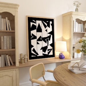 Op de afbeelding: Een ingelijste abstracte kunstprint met een zwart-wit geometrisch ontwerp. Het kunstwerk toont een reeks zwarte vormen tegen een witte achtergrond, wat een moderne en minimalistische esthetiek creëert. De print wordt weergegeven in een licht houten frame.