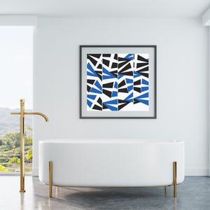Op de afbeelding: Een moderne badkamer met een witte ovale badkuip en gouden armaturen. Aan de muur hangt een ingelijst abstract kunstwerk met blauwe, zwarte en witte geometrische vormen, wat kleur toevoegt aan de minimalistische ruimte.