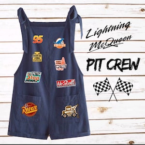Puede incluir: Mono vaquero azul oscuro con m&uacute;ltiples parches con texto y gr&aacute;ficos. Los parches incluyen "95", "Dinoco", "Radiator Springs Curios", "Cozy Cone Motel", "Sputter Stop", "Rusteze", "No Stall" y una gr&uacute;a. Tambi&eacute;n son visibles las palabras "Lightning McQueen" y "PIT CREW".