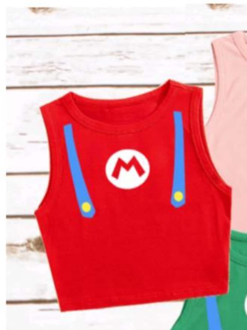 May include: Red crop top with blue suspenders and a white "M" logo, reminiscent of a popular video game character. The sleeveless top has yellow button details and is a vibrant, eye-catching design. A fun and playful garment.