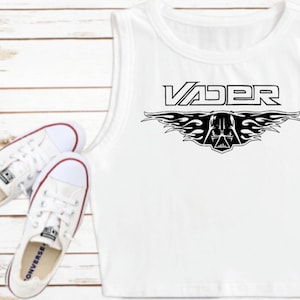 K&ouml;nnte beinhalten: Wei&szlig;es &auml;rmelloses Crop-Top mit einem schwarzen Grafikdruck von Darth Vaders Helm mit Flammen und dem Wort "VADER" dar&uuml;ber.
