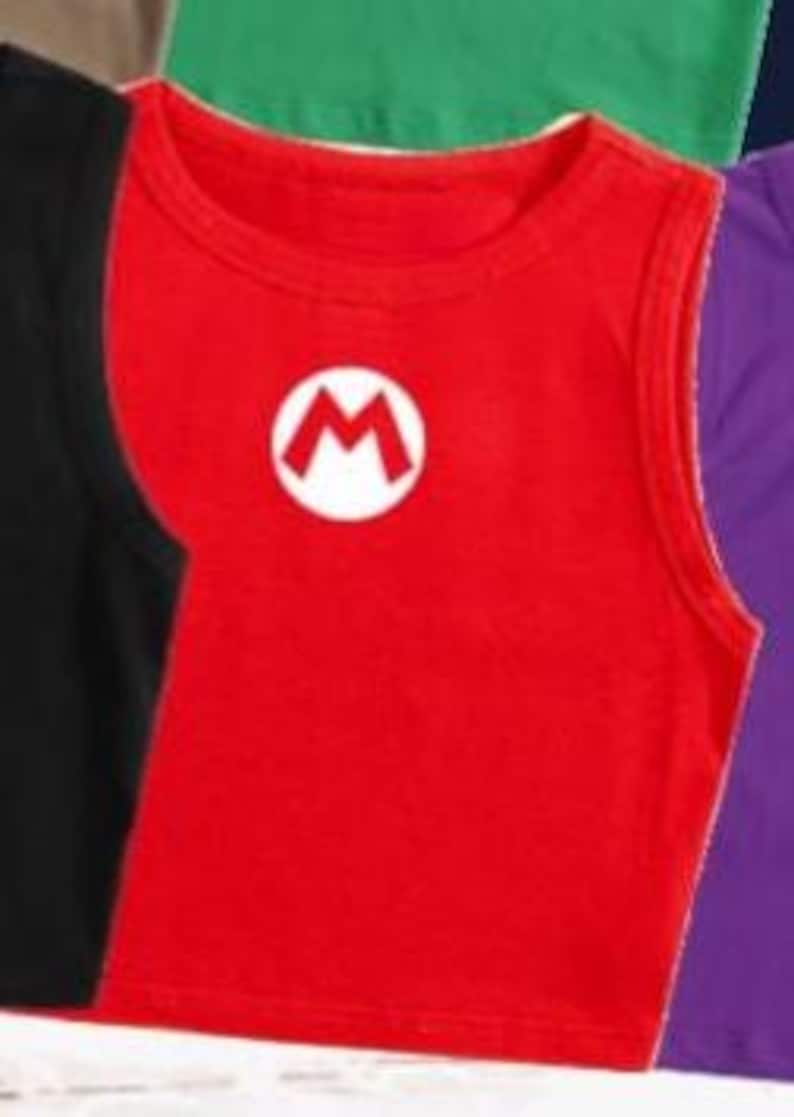 May include: A red crop top with a white circle and a red "M" logo. The sleeveless shirt is made of a soft material and is part of a collection of colorful tops.
