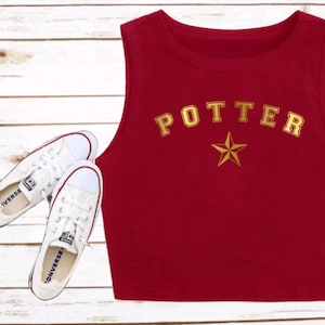 May include: Red sleeveless crop top with the word "POTTER" in gold letters and a gold star.