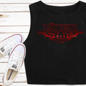 K&ouml;nnte beinhalten: Schwarzes &auml;rmelloses Crop-Top mit einer roten Grafik des Wortes "VADER" mit Flammen und einem Darth-Vader-Helm-Design.