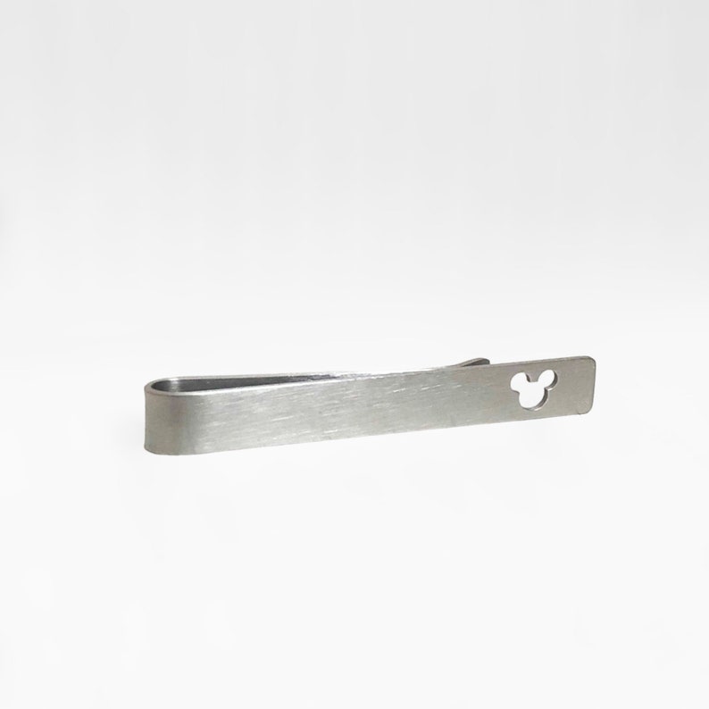 May include: A silver tie clip with a Mickey Mouse silhouette cut out.