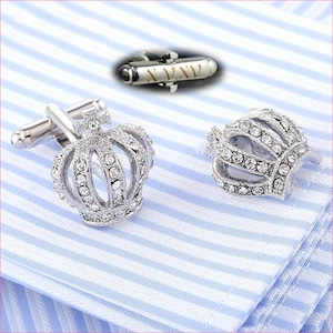 Puede incluir: Un par de gemelos de plata con un diseño de corona. Cada corona está adornada con diamantes de imitación transparentes.