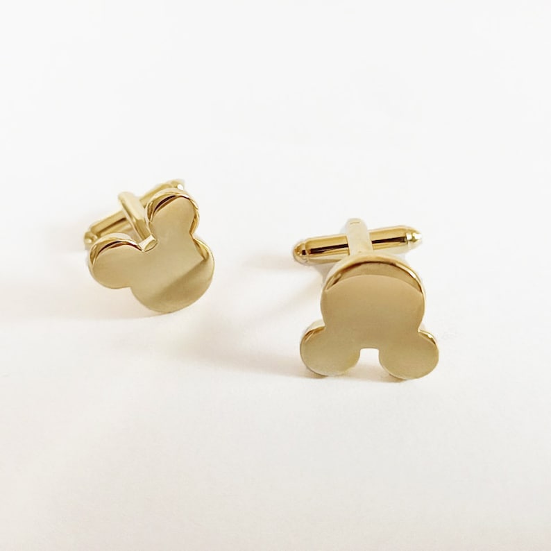 May include: A pair of gold-toned cufflinks with a Mickey Mouse head design.