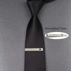 May include: A black tie with a silver tie clip featuring a Mickey Mouse silhouette. The tie clip also has the text "I love you" engraved on it. The text "Personalized Name" is also visible in the image.