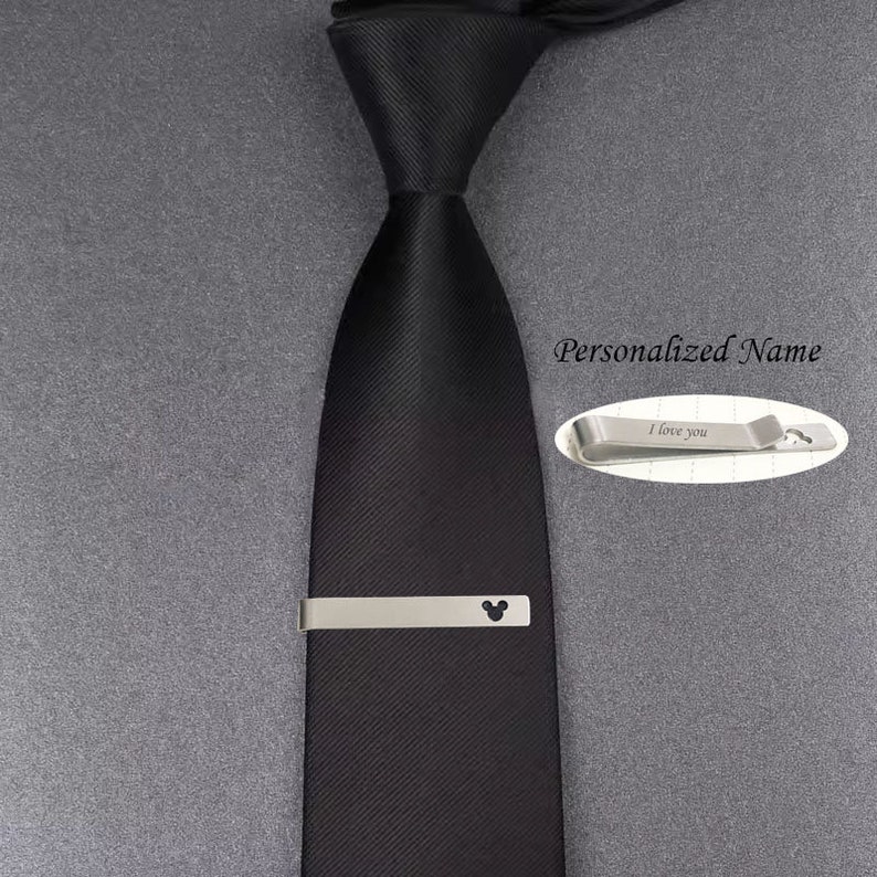 May include: A black tie with a silver tie clip featuring a Mickey Mouse silhouette. The tie clip also has the text "I love you" engraved on it. The text "Personalized Name" is also visible in the image.