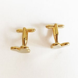 May include: Two gold-tone cufflinks with a butterfly design. The cufflinks are made of metal and have a polished finish.