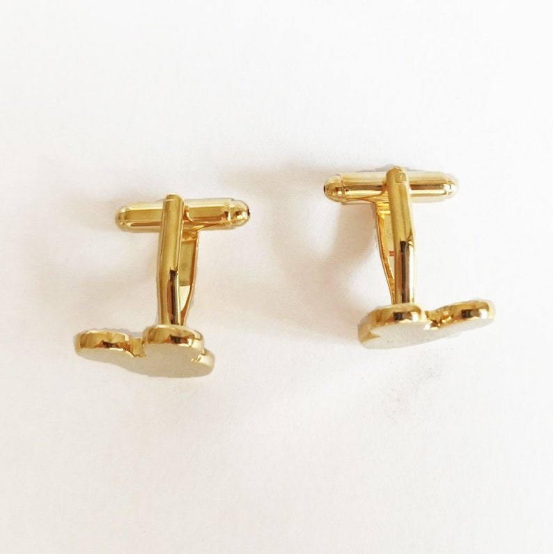 May include: Two gold-tone cufflinks with a butterfly design. The cufflinks are made of metal and have a polished finish.