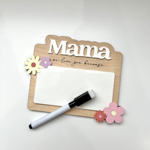 May include: Wooden sign with the word "Mama" in white letters and the text "we love you because" in black script. The sign has a white dry erase surface and comes with a black dry erase marker. The sign is decorated with pink and yellow flowers.