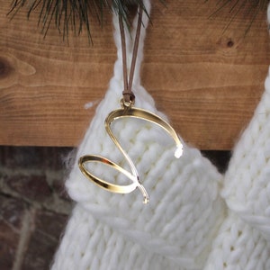 以下が含まれることがあります： 白いニットの靴下と、金色の「S」の文字のオーナメントがぶら下がっている