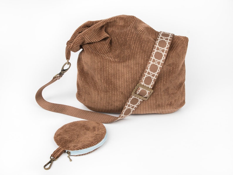 May include: A brown corduroy shoulder bag with a light blue and white patterned strap and a matching brown corduroy coin purse.