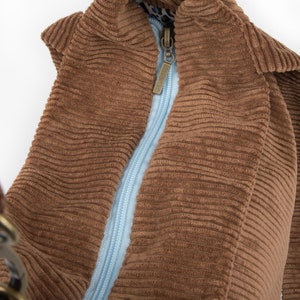 May include: A brown corduroy tote bag with a blue zipper and a metal clasp. The bag is open and the lining is visible.